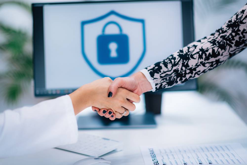 Two people shaking hands in front of a computer screen displaying a lock symbol, suggesting a secure agreement or partnership, perhaps finalized by a notary near Kissimmee, FL.