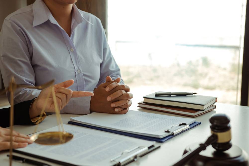 Two people engage in a discussion at a table laden with documents, scales, books, a pen, and a gavel. Nearby is an advertisement for tax preparation near Kissimmee, FL.